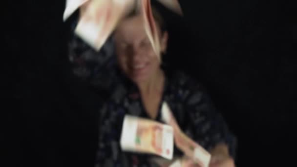 Энтузиастка бросает банкноты пять тысяч рублей на черном фоне, счастливая большая куча денег замедленной съемки акции видео — стоковое видео