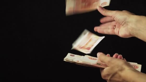 Main féminine disperser cinq mille roubles billets de banque sur fond noir ralenti stock vidéo — Video