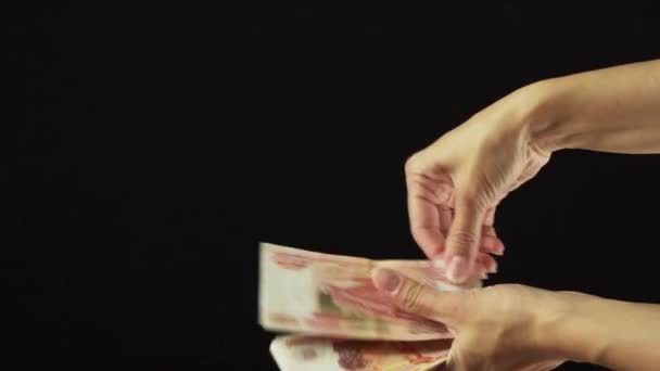 Női kéz scatter bankjegyek ötezer rubel, a fekete háttér lassított stock footage videó — Stock videók