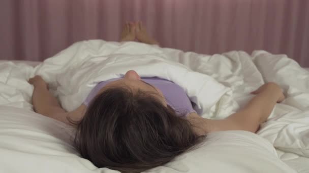 Beautiful teen girl wakes up in bed and smiles stock footage video — Stock Video