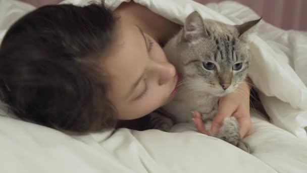 Felice teen girl baci e colloqui con il gatto tailandese a letto magazzino filmato video — Video Stock