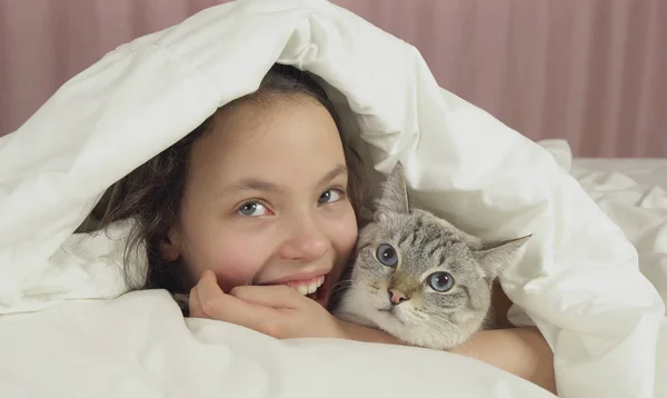 Felice teen girl bacia e parla con il gatto tailandese a letto — Foto Stock