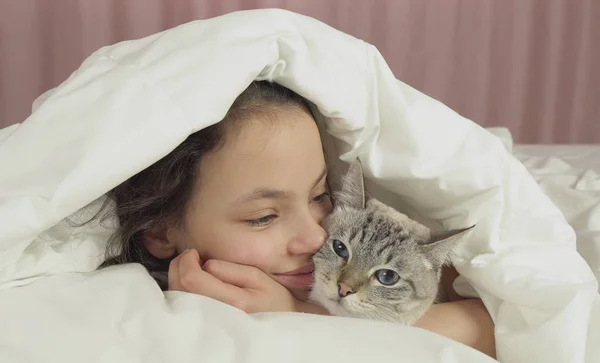 Szczęśliwa dziewczyna całuje i rozmowy z kot tajski w łóżku — Zdjęcie stockowe