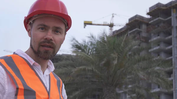 Homem de capacete, arquiteto, engenheiro, gerente conta sobre o progresso da construção à noite — Fotografia de Stock