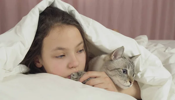 Felice teen girl bacia e parla con il gatto tailandese a letto — Foto Stock