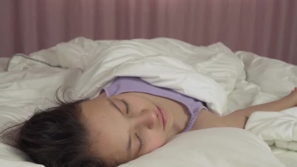 Beautiful teen girl wakes up in bed and smiles stock footage video — Stock Video