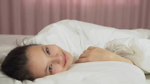 Menina adolescente bonita acorda na cama e sorri — Fotografia de Stock