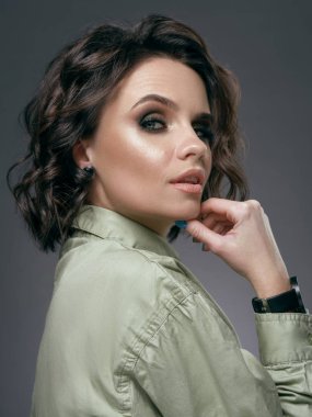 Açık ağız baştan çıkarıcı poz ile model. Akşam makyaj, dumanlı gözler ve çene profili tutan kıvırcık saçlı kadın ile atış, haki elbise ve bilek seyretmek