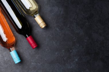 Kırmızı, gül ve beyaz şarap şişeleri taş masada. Kopya alanı ile üstten görünüm