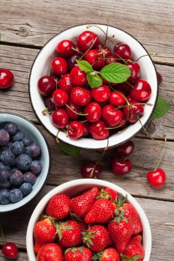 Taze yaz meyveleri. Kiraz, böğürtlen ve çilek kase ahşap arka plan üzerinde. Üstten görünüm