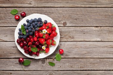 Taze yaz meyveleri. Kiraz, böğürtlen ve çilek kase ahşap arka plan üzerinde. Kopya alanı ile üstten görünüm 