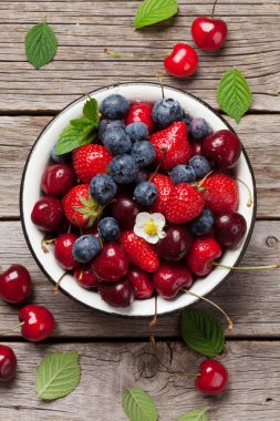 Taze yaz meyveleri. Kiraz, böğürtlen ve çilek kase ahşap arka plan üzerinde. Üstten görünüm