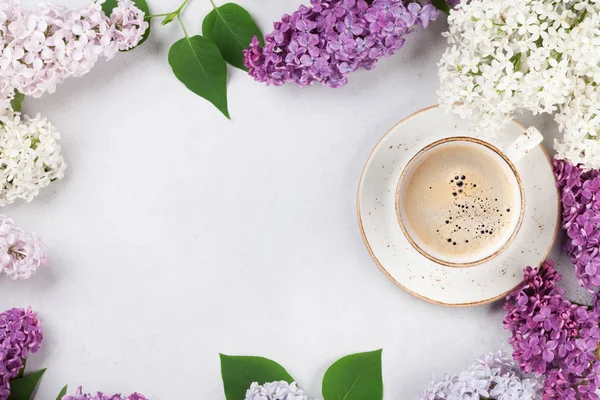 Colorful lilac flowers and coffee cup over stone background. Top view with space for your text