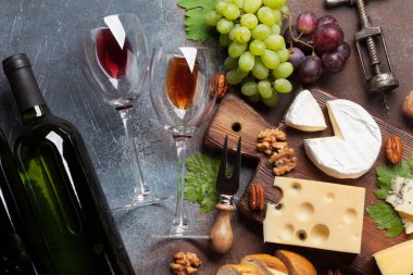 Şarap, peynir, üzüm, ekmek ve karanlık taş zemin üzerine fındık. Üstten görünüm