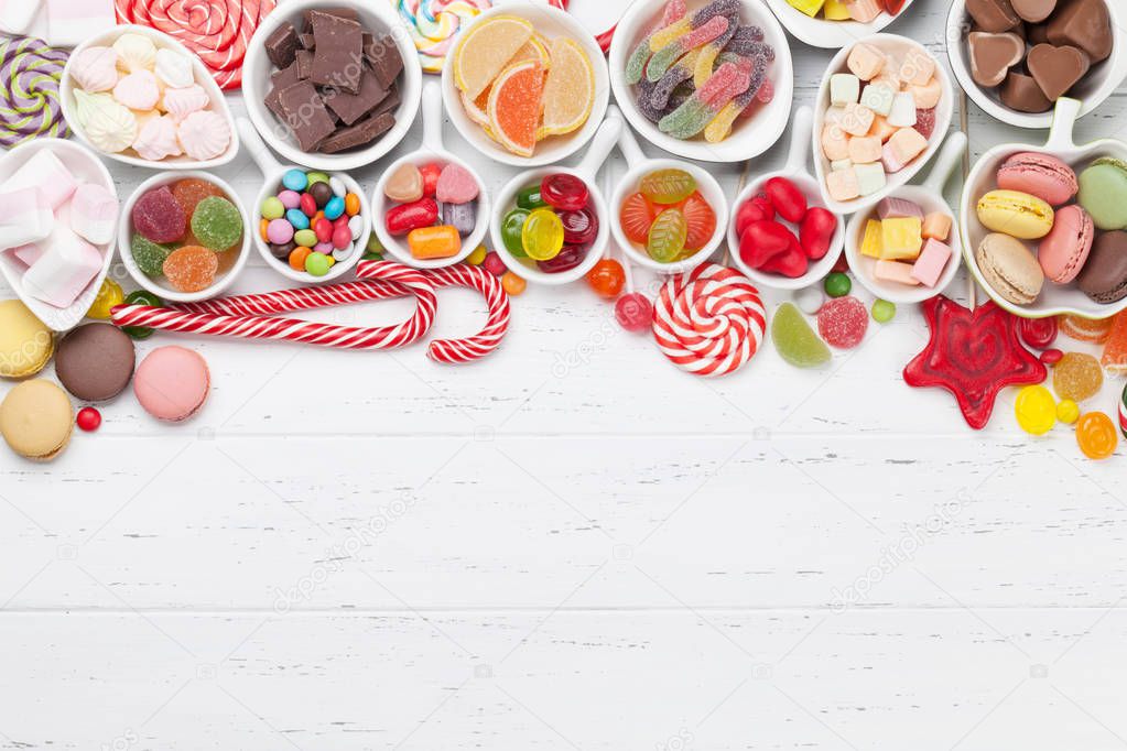 Colorful sweets. Lollipops, macaroons, marshmallow, marmalade, chocolate and candies. Top view with space for your greetings