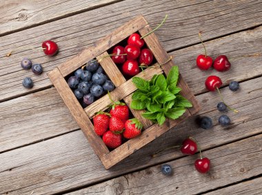 Taze yaz meyveleri kutusu. Kiraz, yaban mersini, çilek ve nane. Üstten görünüm