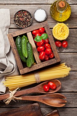 Makarna ve malzemeler. Domates, fesleğen, salatalık ve baharat. Pişirme kavramı. Üstten görünüm
