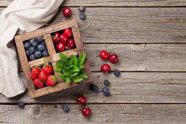 Taze kiraz, yaban mersini, çilek ve nane ahşap kutusunda. Metin alanı olan üstten görünüm