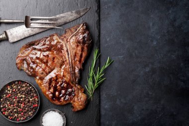 Grilled T-bone steak on stone table. Top view with copy space