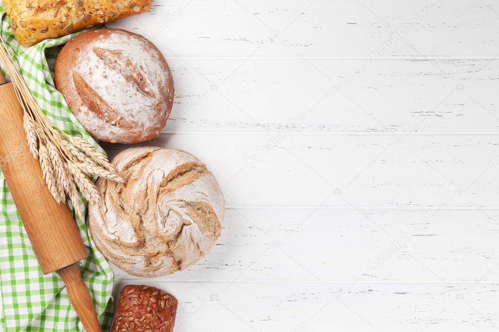 Various crusty bread on white wooden background. Top view with space for your text