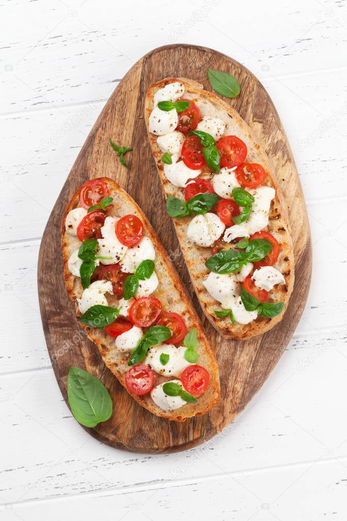 Caprese bruschetta toasts with cherry tomatoes, mozzarella and basil. Top view