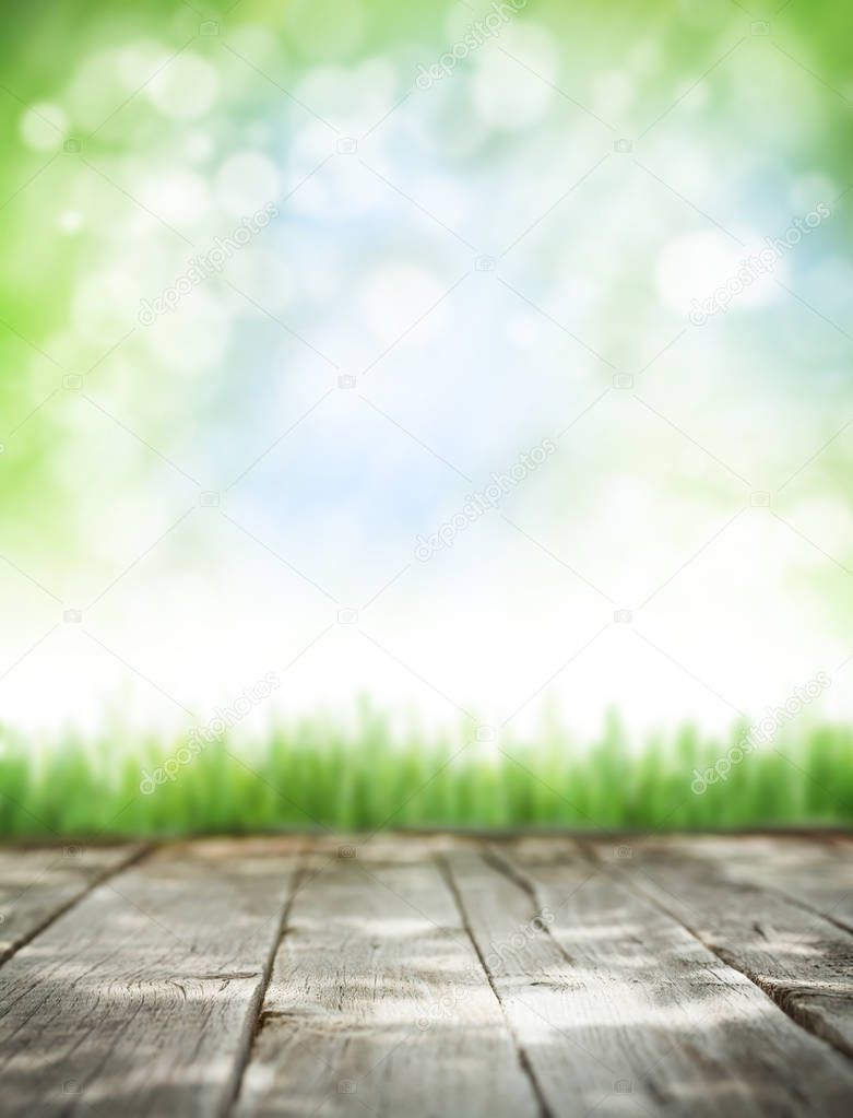 Abstract sunny summer background with wooden table, grass and blue sky. Copy space for your product. Toned
