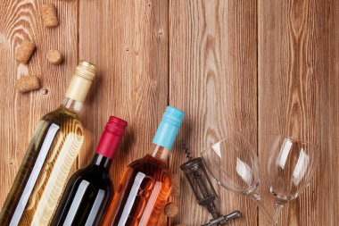 Ahşap masa üzerinde şarap şişeleri. Kırmızı, gül ve beyaz şarap. Metin alanı olan üstten görünüm