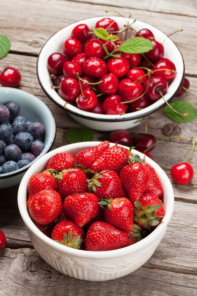 Taze yaz meyveleri. Kiraz, böğürtlen ve çilek kase ahşap arka plan üzerinde
