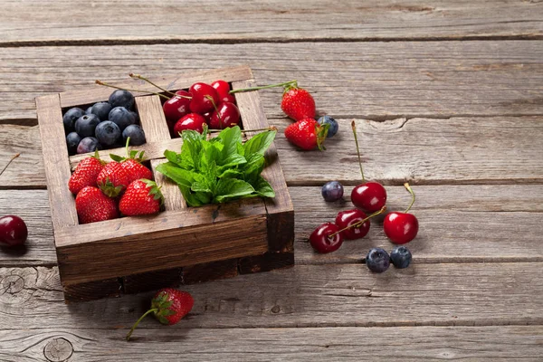 Kiraz, böğürtlen ve çilek ve nane ahşap kutusunda. Senin metin için ile yer