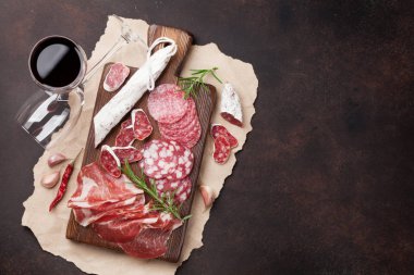 Salam, jambon, sosis, jambon, pastırma ve kırmızı şarap cam dilimlenmiş. Et meze tabağı taş masada. Kopya alanı ile Üstten Görünüm