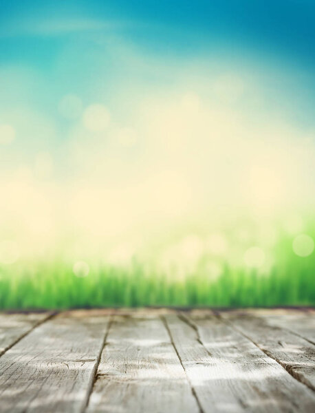 sunny summer background with wooden table, grass and blue sky. Copy space for your product. Toned