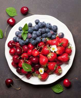 Taze yaz kiraz, böğürtlen ve çilek plaka üzerinde. Üstten görünüm