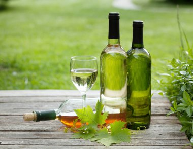 Ahşap masa üzerinde beyaz şarap şişeleri. Açık natürmort. Senin metin için ile yer