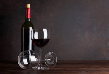 Kırmızı şarap şişesi ve tahta duvar önünde bardak. Metniniz için kopya alanı ile