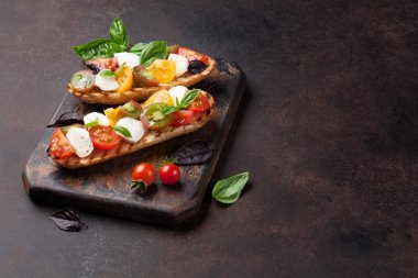 Bruschetta kiraz domates, mozzarella ve fesleğen ahşap tahta üzerinde. Caprese salatası. Kopya alanı ile