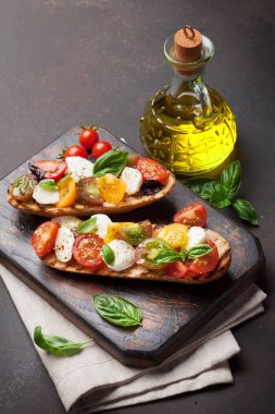 Kirazlı domates, mozzarella ve ahşap tahtada fesleğen. Caprese salatası