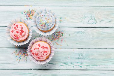 Ahşap masa üzerinde renkli dekor ile tatlı cupcakes. Selam yeri olan Üstten Görünüm