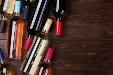 Ahşap masa üzerinde şarap şişeleri. Kırmızı, gül ve beyaz şarap. Metin alanı olan üstten görünüm