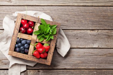 Taze yaz meyveleri kutusu. Kiraz, yaban mersini, çilek ve nane. Üstten görünüm alanı ile 