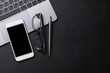 Ofis malzemeleri, akıllı telefon ve siyah ahşap masa üstünde laptop. Düz yatıyordu. Metin alanı olan üstten görünüm