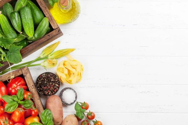 Fresh garden tomatoes, cucumbers and pasta on cooking table. Top view with space for your text