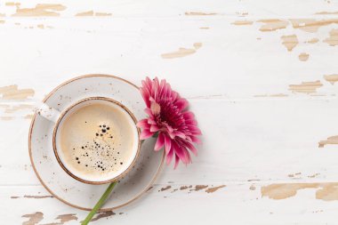 Kahve fincanı ve gerbera Beyaz ahşap masanın üzerine çiçek. Metin alanı olan üstten görünüm
