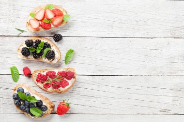 Beyaz ahşap zemin üzerinde çilek ile brushetta. Kopya alanı ile üstten görünüm