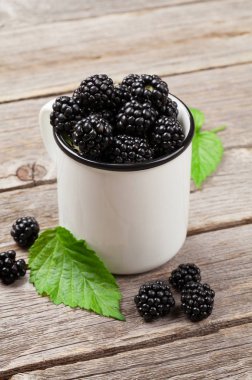 Ahşap masa üzerinde olgun böğürtlen fincan