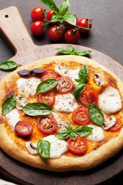 İtalyan pizza domates, mozzarella ve kesme tahtası üzerinde fesleğen ile