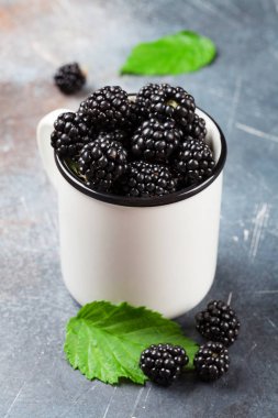 Taş masada olgun böğürtlen fincan