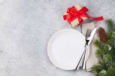 Taş zemin üzerine kar tarafından Noel tablo ayarını hediye kutusu ve köknar ağacı dalı ile kaplı. Boş tabak, çatal ve bıçak. Selam yeri olan üstten görünüm