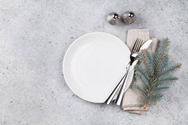 Noel tablo ayarı ile taş zemin üzerine boş tabak, çatal bıçak ve köknar ağacı dalı. Selam yeri olan üstten görünüm