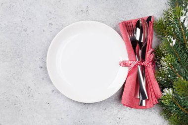 Taş zemin üzerine kar tarafından Noel tablo ayarını boş tabak, çatal bıçak ve köknar ağacı dalı ile kaplı. Selam yeri olan üstten görünüm