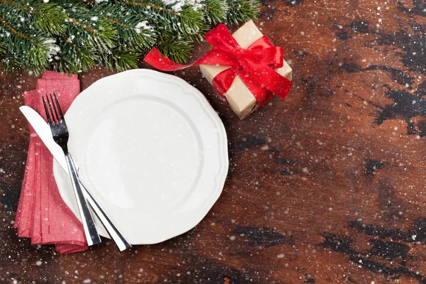 Ahşap arka plan üzerinde kar tarafından Noel tablo ayarını hediye kutusu ve köknar ağacı dalı ile kaplı. Selam yeri olan üstten görünüm